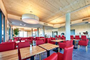 a restaurant with wooden tables and red chairs at Hotel 2050 in Rutesheim