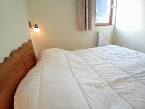 un lit blanc dans une chambre avec une fenêtre dans l'établissement Apartment with balcony for 6 people, à Val Cenis
