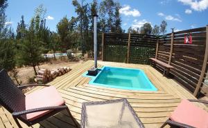 a swimming pool on a wooden deck with two chairs at Cabañas constitucion in Constitución