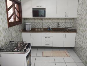 a kitchen with white cabinets and a stove top oven at Casa em Itapoá in Vila Velha