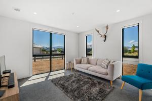 a living room with a couch and a blue chair at The Alpine Patch - Wanaka Holiday Home in Wanaka