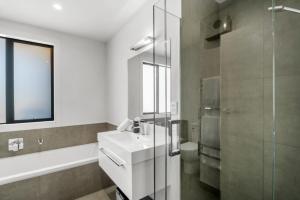 a white bathroom with a sink and a shower at The Alpine Patch - Wanaka Holiday Home in Wanaka +15 photos