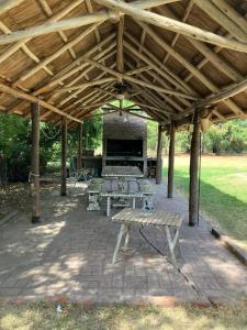 a wooden pavilion with benches and a picnic table at Gran Quinta en Mercedes con piscina in Mercedes