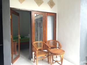 two wooden chairs sitting next to a window at Linggy Homestay in Nusa Lembongan