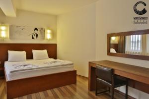 a room with a bed and a desk and a mirror at Hotel Centrum Prizren in Prizren