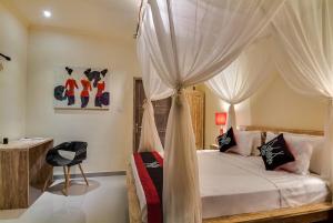 a bedroom with a canopy bed with white curtains at Villa Toto Seminyak in Seminyak +20 photos