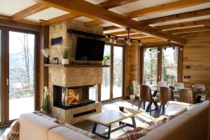 a living room with a fireplace and a table and chairs at Tara Cozy Home in Mokra Gora