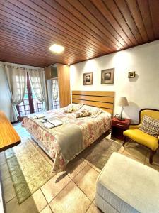 Un dormitorio con una cama grande y una silla amarilla. en VHL Apartamentos, en Campos do Jordão
