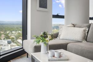 a living room with a couch and a table with flowers at High-Rise 3-Bed Apartment with Premium Amenities in Box Hill