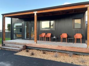 a house with orange chairs sitting on a deck at The Waimate Lodges in Waimate