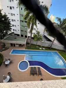 a swimming pool with chairs and a table and a building at Flat Rosarinho II - Confortável e Super Completo in Recife