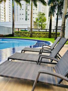 two lounge chairs sitting next to a swimming pool at Flat Rosarinho II - Confortável e Super Completo in Recife