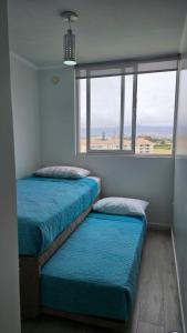 two beds in a room with a large window at Departamento Edificio Playa Blanca in La Serena