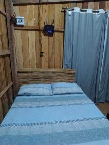 a bedroom with a bed with blue sheets and a curtain at La Casa Magno's Ajuruteua in Bragança