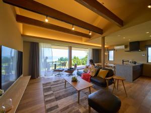a living room with two people sitting on the couch at 瀬戸内ゴルフリゾートヴィラ in Takekara