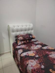 a bedroom with a bed with a quilt and pillows at Puteri Homestay in Kangar