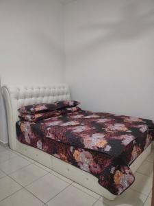 a bedroom with a bed with a floral quilt at Puteri Homestay in Kangar