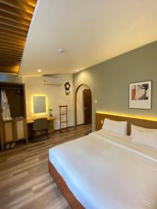 a bedroom with a large white bed and a desk at A25 Hotel - 14 Hồ Huấn Nghiệp in Ho Chi Minh City