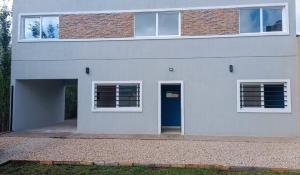 una casa blanca con una puerta y ventanas azules en El Buen Vivir, en Mar del Plata