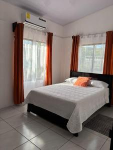 a bedroom with a large bed with orange curtains at Casa Celeste Río Grande in Paquera +52 photos