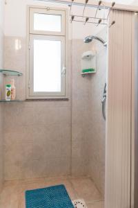 łazienka z prysznicem z oknem i niebieskim dywanem w obiekcie Il Paesino - La Veranda w mieście Licodia Eubea