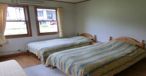 deux lits dans une chambre avec deux fenêtres dans l'établissement Pension Come Relaxing Western-style room- Vacation STAY 14977, à Minami Uonuma
