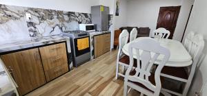 a kitchen with a table and white chairs in it at La Frontera Departamento in Tulcán