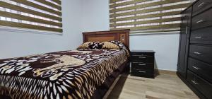 a bedroom with a bed and a dresser at La Frontera Departamento in Tulcán