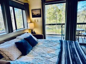 a bed with blue pillows in a bedroom with windows at Inside Yosemite Park-Cozy Corner Unit-Sleeps 2 in Yosemite West