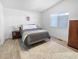 a white bedroom with a bed and a window at Bark and Bike Abode home in Fruita