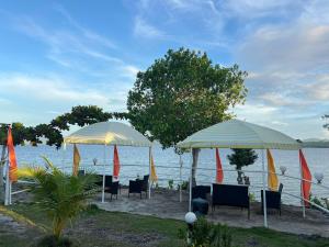 two umbrellas and chairs on a beach near the water at Coast Side Cliffs Resort in Talisay