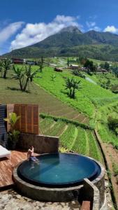 a man sitting in a swimming pool in a field at Villa The Noman Tawangmangu by Suasana Villa in Sarangan