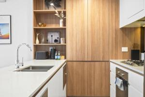 a kitchen with a sink and wooden cabinets at Waterview Apt at Wentworth Point in Sydney