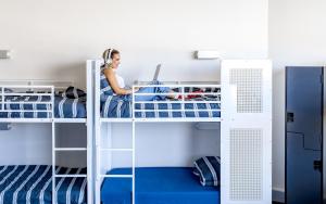 een vrouw die werkt aan een laptop in een stapelbed bij Wake Up! Sydney Central in Sydney