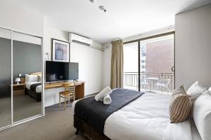 a bedroom with a bed and a desk with a television at Retreat Horizons - Spacious Perth CBD 1BR in Perth +22 photos