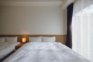 a bedroom with a large white bed and a window at Coda House in Aoichō