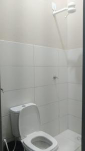 a white bathroom with a toilet and a shower at Hotel America 2 in Tangara da Serra