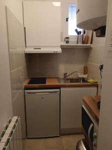 a small kitchen with white cabinets and a sink at Séduisant studio confortable in Orléans +6 photos