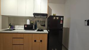 a kitchen with a black refrigerator and wooden cabinets at Setia Alam Edu Sentral 27 in Shah Alam +13 photos