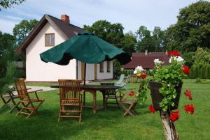 una mesa con sillas y una sombrilla frente a una casa en Brīvdienu Māja Riekstnieki en Plieņciems