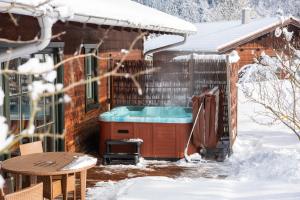 a hot tub outside of a house in the snow at Beim Waicher Chalets & Suiten zwischen Salzburg und Chiemsee in Ruhpolding