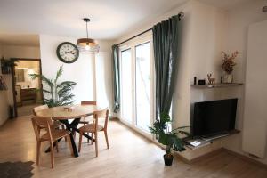 een woonkamer met een tafel en een klok aan de muur bij Le Refuge Tropical Taine in Annecy