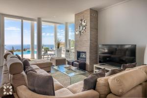 a living room with a large couch and a television at Villa Punta Vista by Abahana Villas in Cumbre del Sol