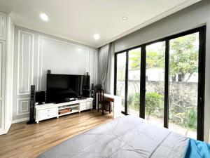a bedroom with a flat screen tv and a large window at J'adore Garden House Vinh Yen in Nhân Mỹ