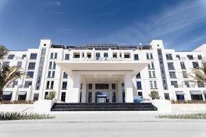 a large white building with stairs in front of it at Luxury Seaside Stay - SeaBreeze The Grand in Nardaran