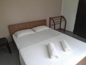 a white bed with two pillows and a chair at Gloria Cottage Non AC in Negombo +5 photos