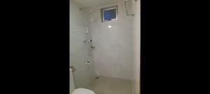 a white bathroom with a toilet and a window at Gloria Cottage Non AC in Negombo