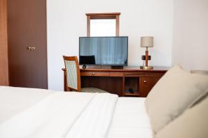 a bedroom with a bed and a desk with a television at Hotel Zvezda in Murska Sobota