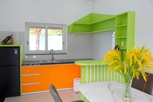 a kitchen with orange and green cabinets and a table at Blue Diamond Homestay in Ấp Bình Phú