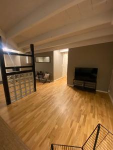 an empty living room with wooden floors and a flat screen tv at Dronningens Gate 95, 0402 Kristiansand in Kristiansand
